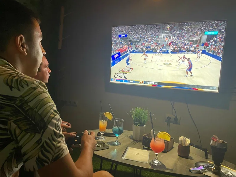Гости играют в баскетбол на PlayStation за столом с напитками